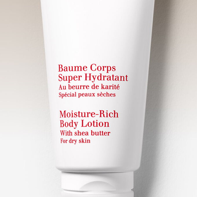 Clarins Moisture-Rich Body Lotion among orange tree leaves and shea nuts to illustrate the natural origin of the ingredients.