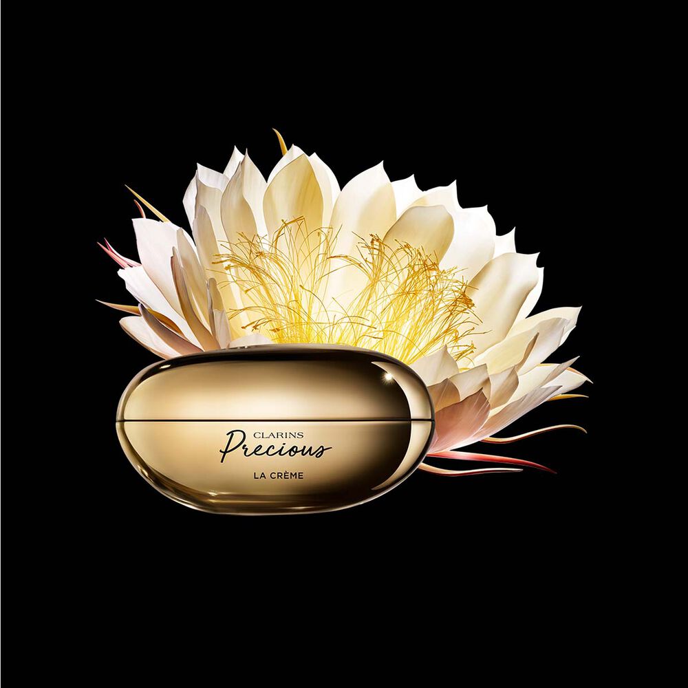 Packshot of Clarins Precious Soft Cream close to a Moonlight flower on dark background.