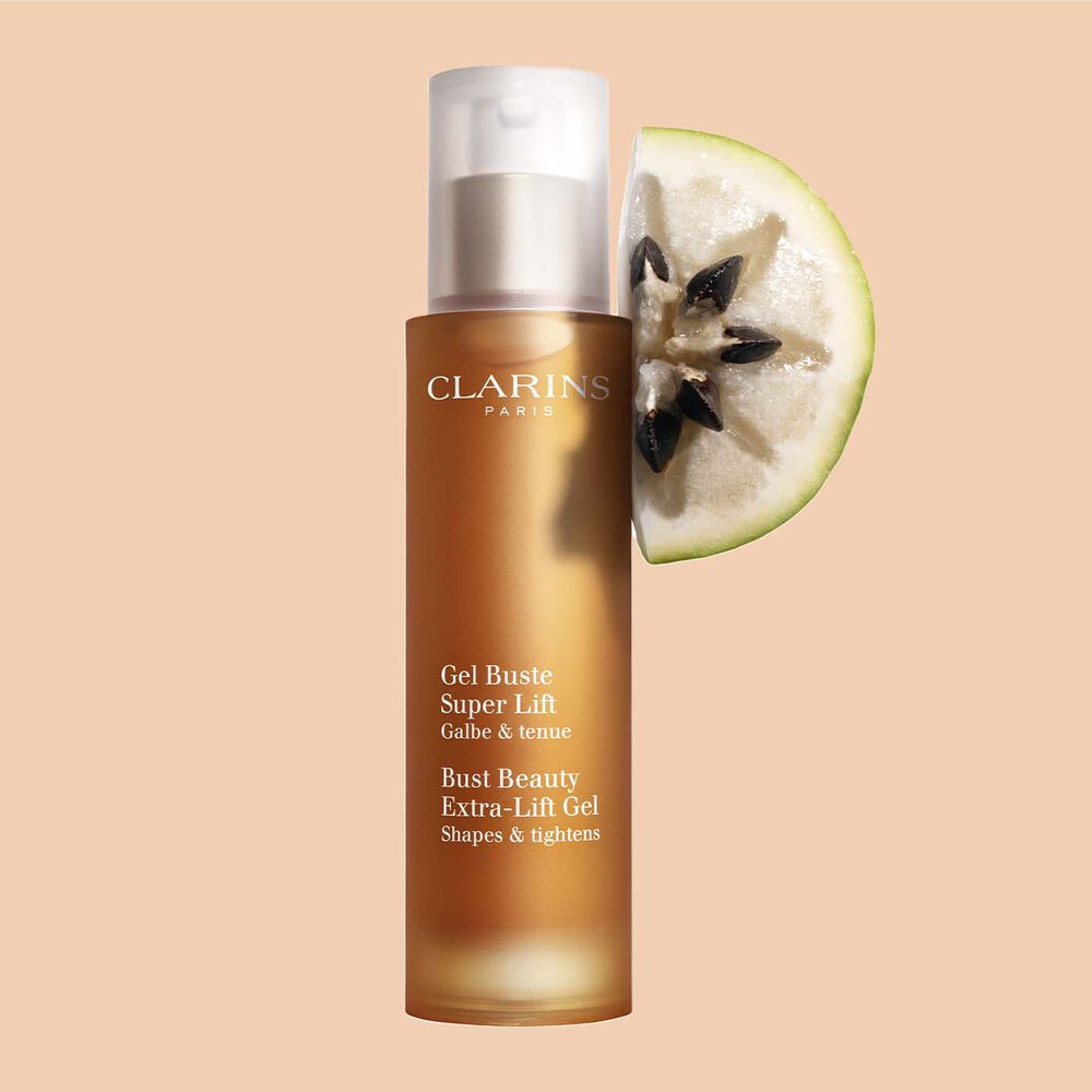 A bottle of Clarins Bust Beauty Extra-lift Gel close to a slice of Vu Sua fruit on a peach background.