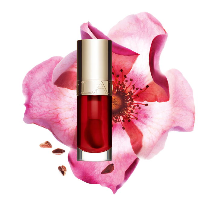 Packshot of Clarins Lip Comfort Oil Strawberry, placed next to a sweetbriar rose on a light pink background.