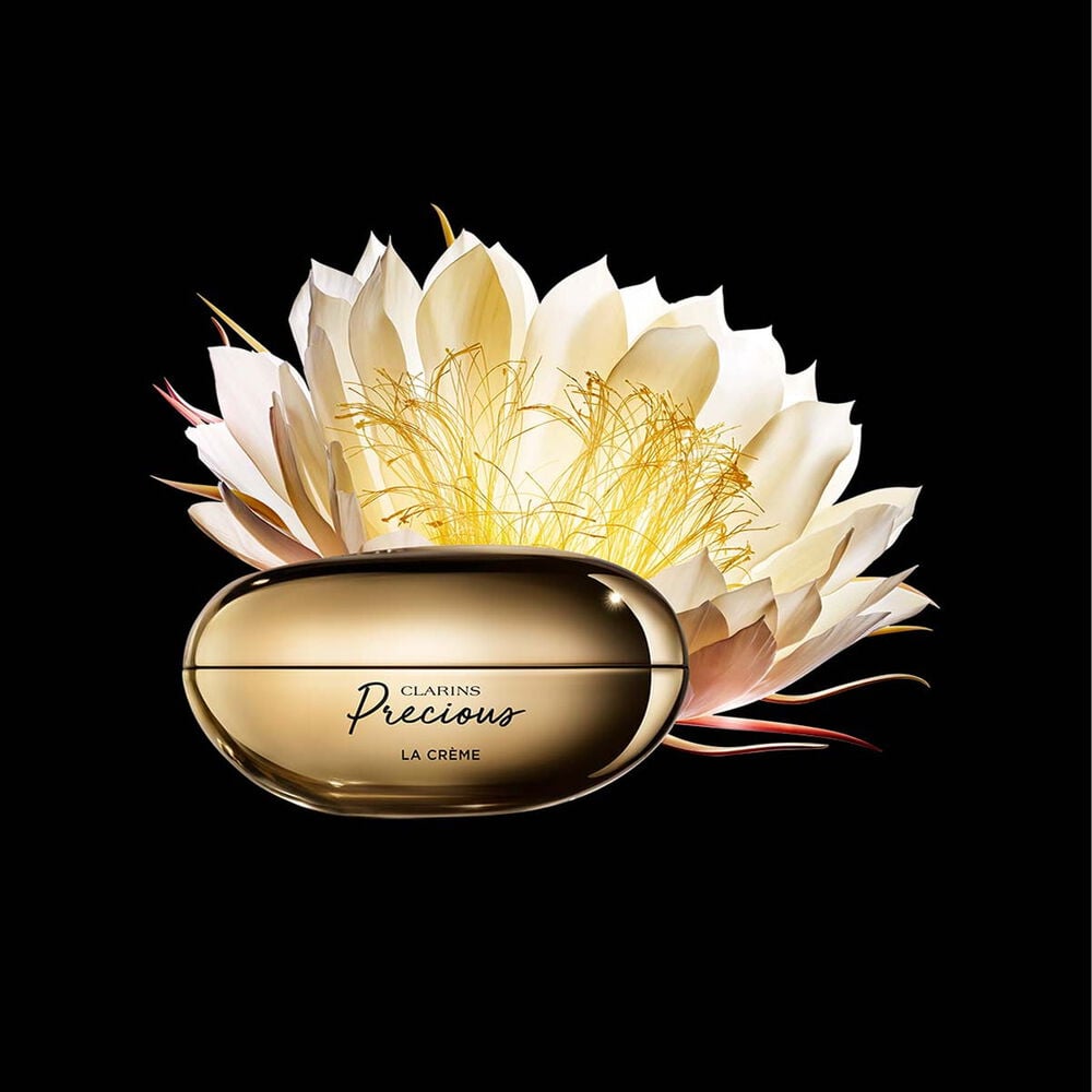 Packshot of Clarins Precious Soft Cream close to a Moonlight flower on dark background.