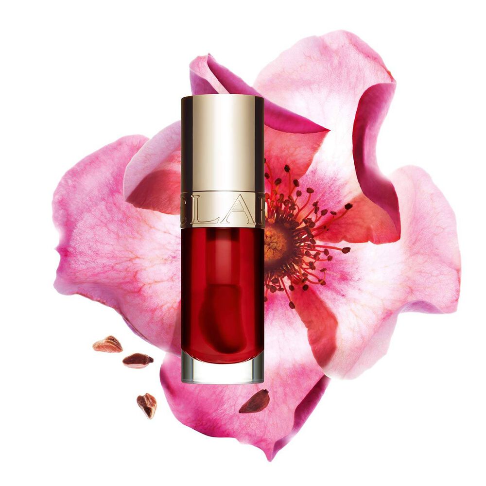 Packshot of Clarins Lip Comfort Oil Strawberry, placed next to a sweetbriar rose on a light pink background.