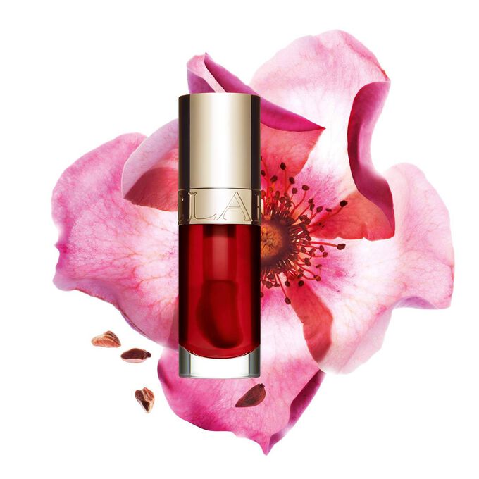 Packshot of Clarins Lip Comfort Oil Strawberry, placed next to a sweetbriar rose on a light pink background.