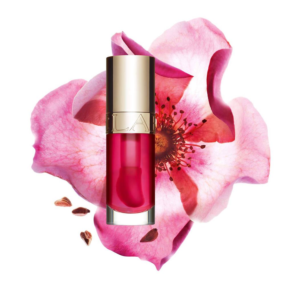 Packshot of Clarins Lip Comfort Oil in Pitaya, placed next to a sweetbriar rose on a light pink background.