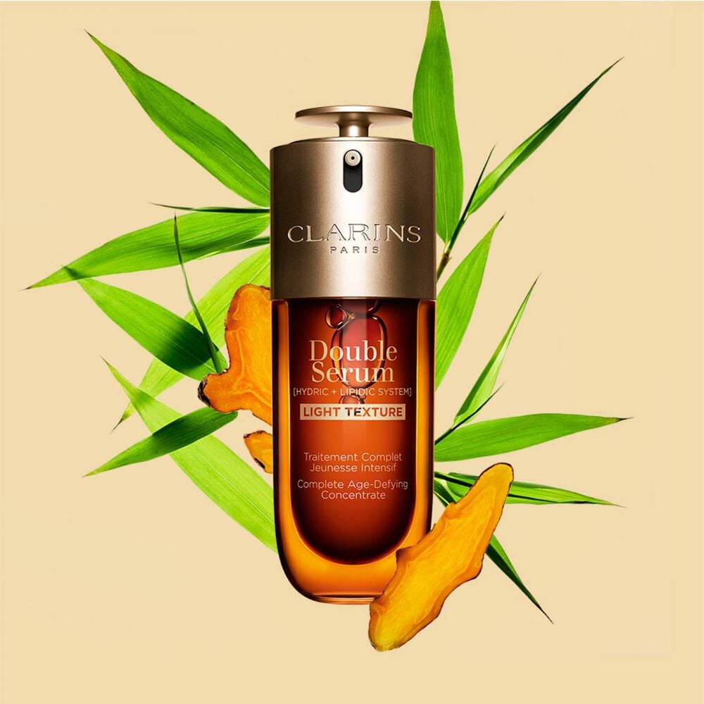 A 50ml bottle of Clarins Double Serum Light Texture among turmeric and provençal reed leaves against an orange background. A 50ml bottle of Clarins Double Serum Light Texture among turmeric and provençal reed leaves against an orange background.