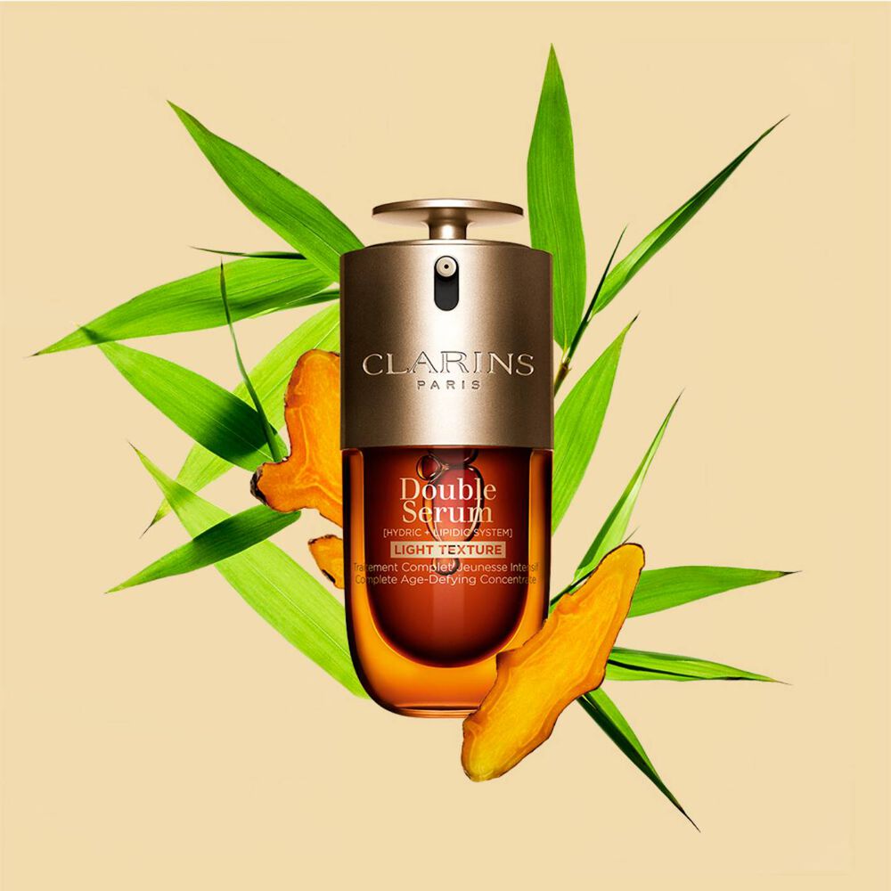 A 50ml bottle of Clarins Double Serum Light Texture among turmeric and proven&ccedil;al reed leaves against an orange background.